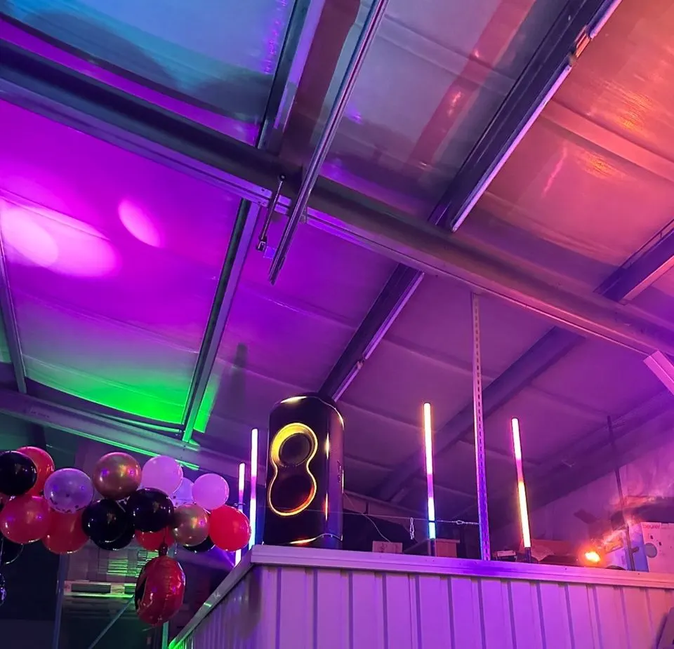 Die PartyBox auf einer Feier unter einem Glasdach, mit Luftballons und bunter Beleuchtung
